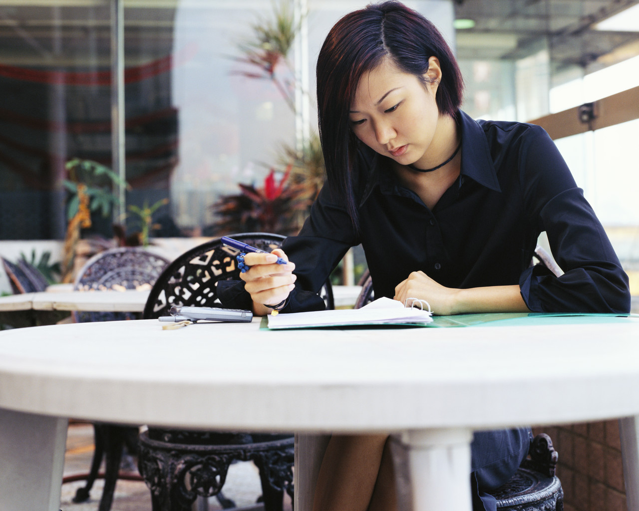 Woman at a talble, writing in a notebook